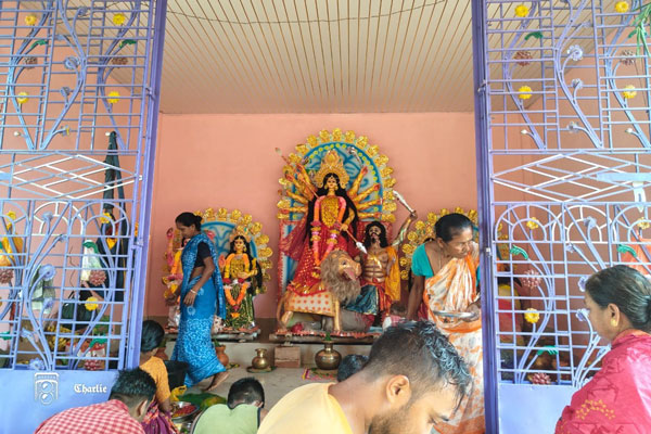 A vibrant scene of Basanti Puja celebrations in Kalyanpur, Tripura, where devotees gather at a temple pandal on Maha Saptami.