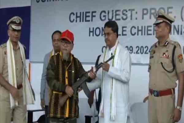Tripura Chief Minister Dr. Manik Saha accepting a firearm from a surrendered militant leader in traditional attire during a formal Joining Mainstream Ceremony in Jampuijala under the West Tripura district..
