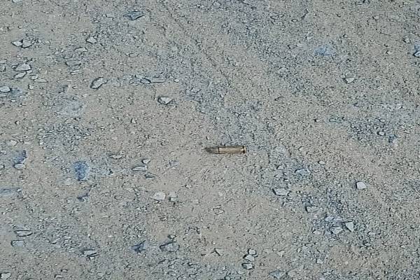 A spent brass bullet shell lying on a dusty, gravel-covered road in Tripura, indicating a recent firing incident.