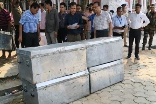 Election officials inspecting large metal trunks containing EVMs at Umakanta Ground, Agartala, for the 2026 TTAADC elections.