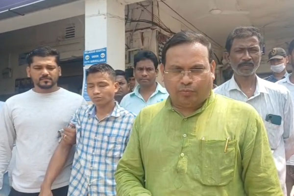 Minister Kishore Barman inspecting a damaged party booth office in Rampada Bari ADC Village, Tripura, surrounded by security and local residents.