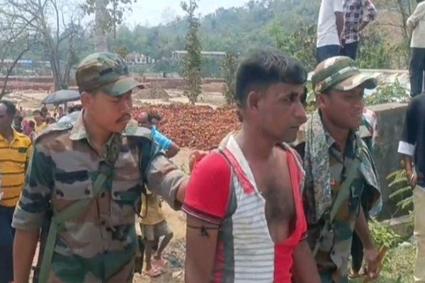 TSR personnel and police escorting accused Bachhut Ali through a crowd of villagers near a brick kiln in Kailashahar, Tripura.