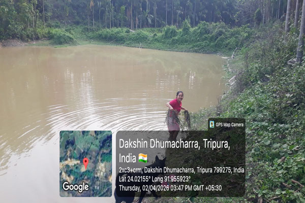 A woman from the tribal community in Dakshin Dhumacharra, Tripura, harvesting aquatic plants/fish in a rural pond, documented via GPS Map Camera on April 2, 2026.