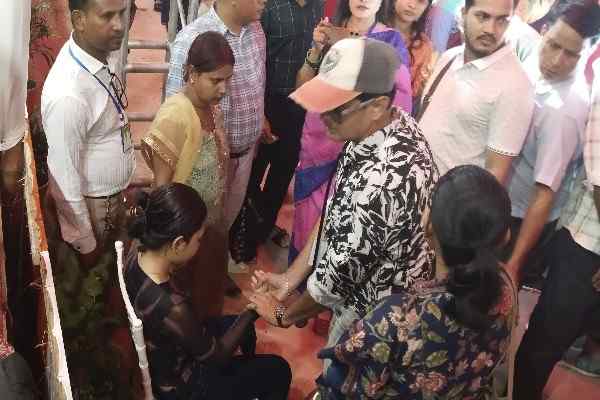 Doctor examining a young female attendee sitting on a chair assisted by volunteers and disaster management staff at Mayer Gamon 2026 event in Agartala